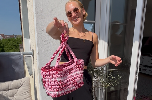 woman holding a pink and red crochet bag, cover image of a simple crochet bag tutorial