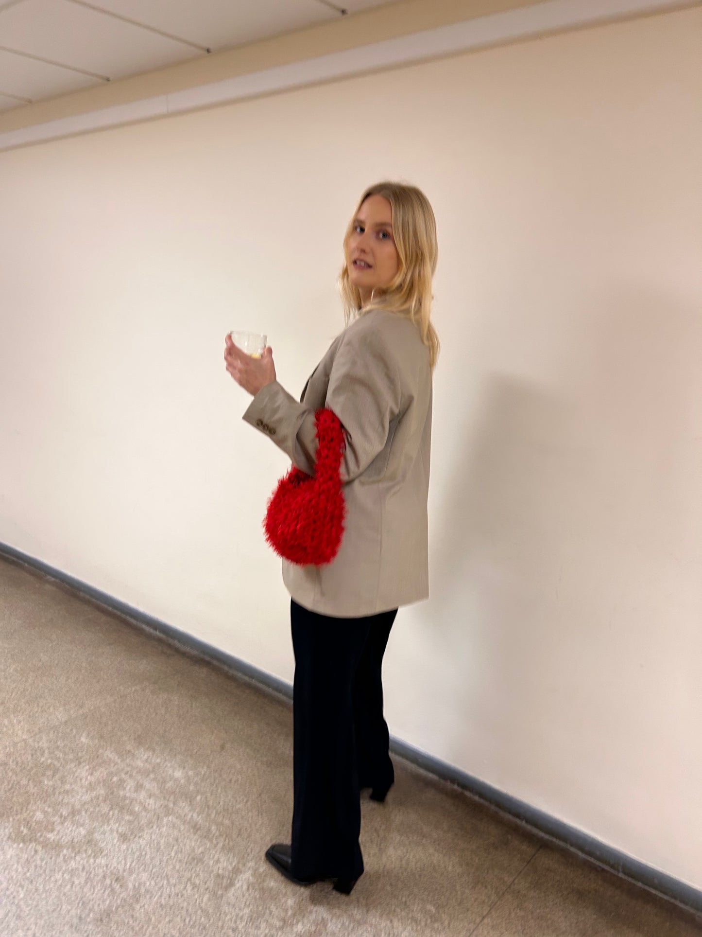 Woman holding a red bag against a plain wall