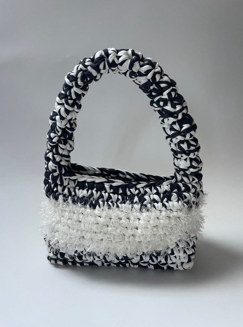 Black and white crochet bag  with white fluffy detailing in the middle 