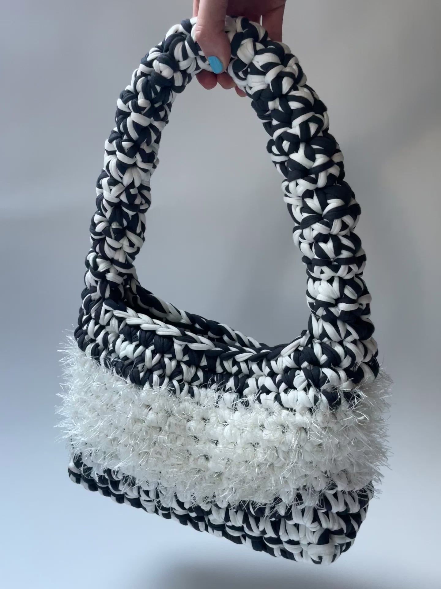 Black and white crochet bag with white fluffy detailing in the middle